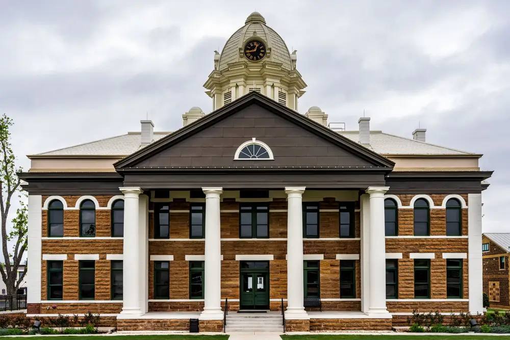 A county courthouse with white columns and a clock cupola on a cloudy day
